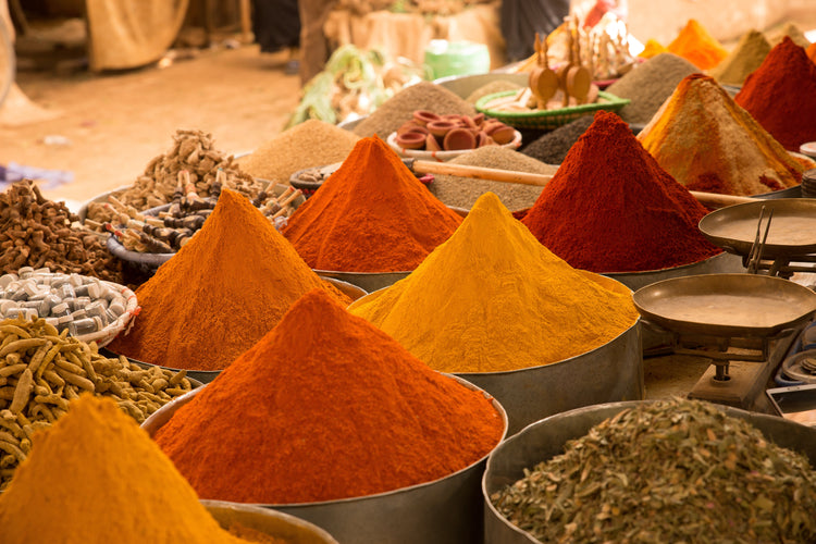 Colorful spice piles at an open Asian market with metal bowls and dried herbs, Naturia