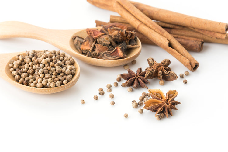 Chinese five spice ingredients on white background with cinnamon, star anise, and coriander