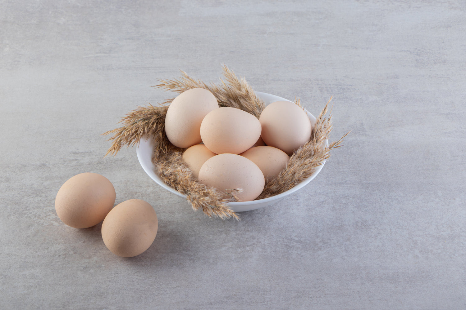 Fresh white chicken eggs in a bowl on stone surface, Naturia organic food concept