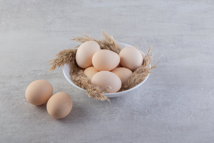 Fresh white chicken eggs in a bowl on stone surface, Naturia organic food concept